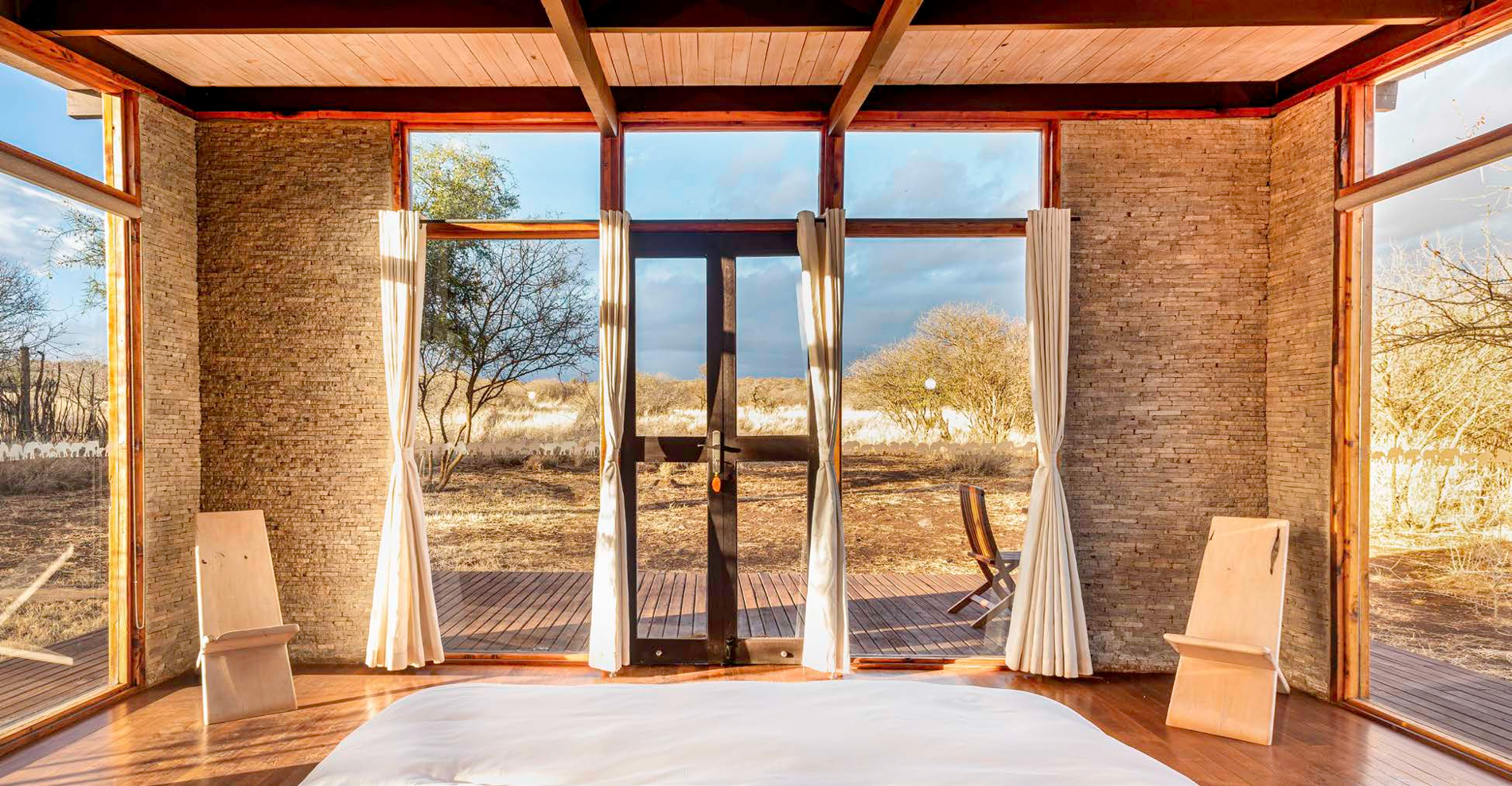 Sunlit interior with large glass doors opening onto a natural landscape