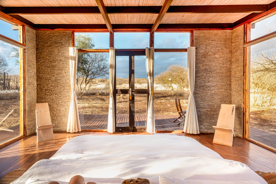 Sunlit interior with large glass doors opening onto a natural landscape