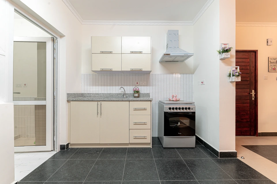 Compact kitchen with pale cabinetry, an extractor hood, and a cooker