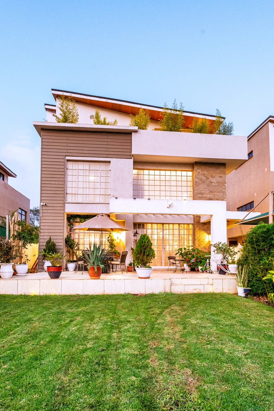 Modern house with balconies, large windows, and landscaped grounds