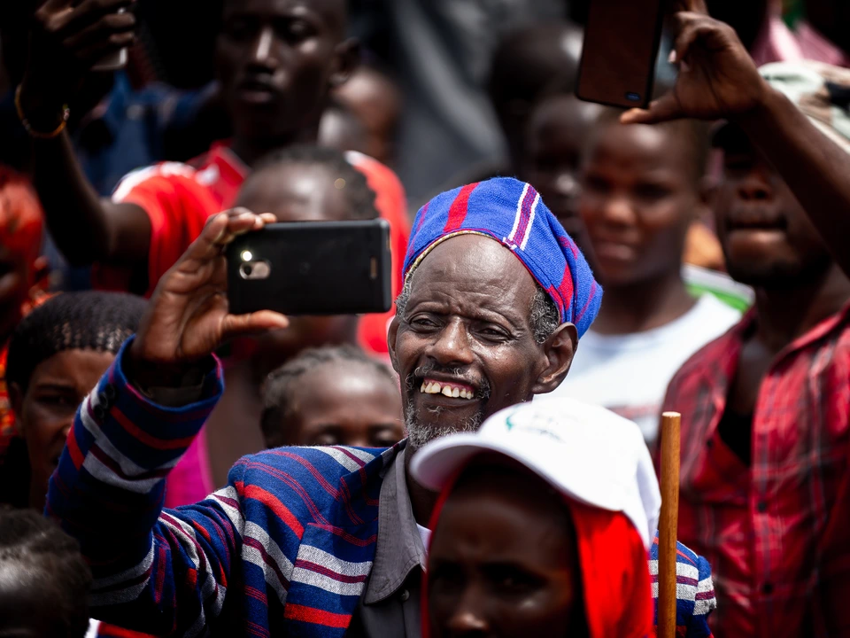 People watching a cultural event, including a man recording with his phone