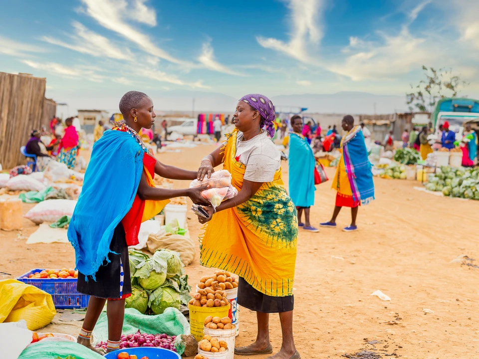 Two people meeting at an outdoor market beneath a blue sky