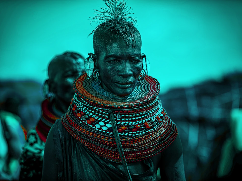 Portrait of a person wearing elaborate beadwork under blue stage lighting