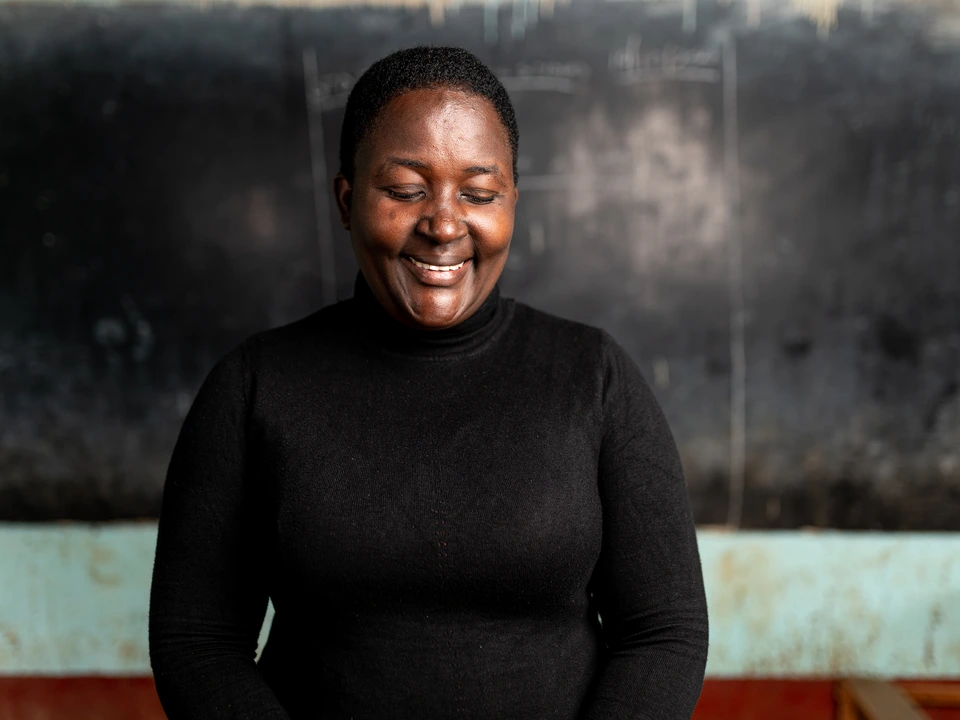 Smiling woman in a black top standing against a textured wall