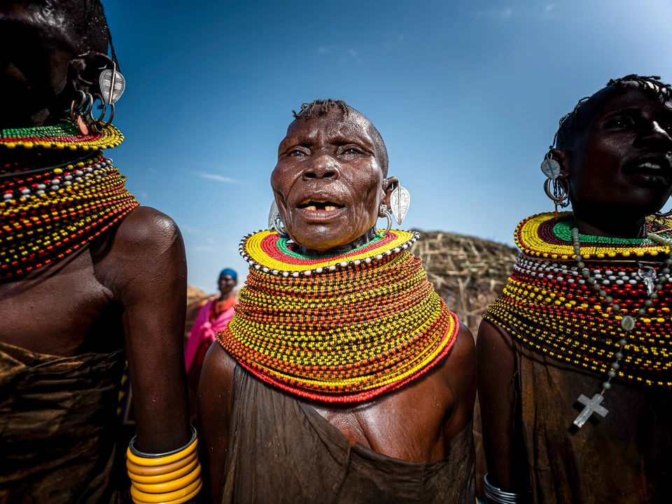 Women wearing traditional layered beadwork beneath a clear blue sky