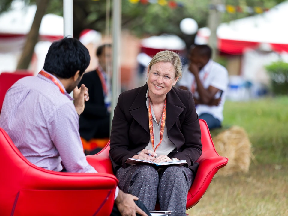 Two people in conversation while seated in red chairs outdoors