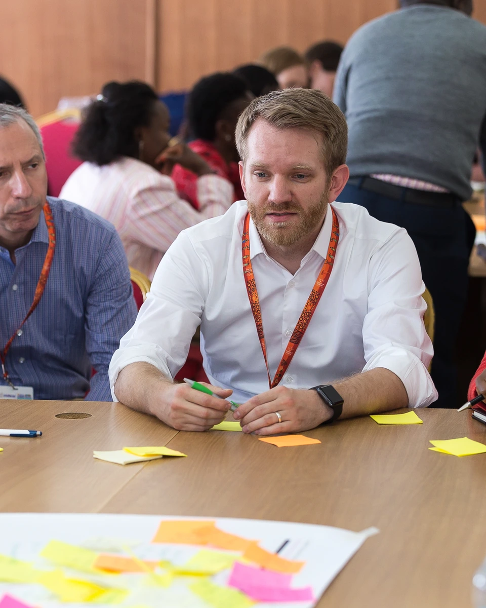 Conference participant listening at a table during a meeting