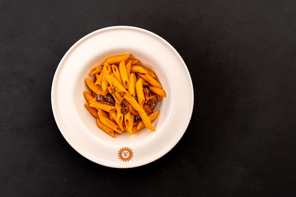 Overhead photograph of pasta on a white plate against a dark tabletop
