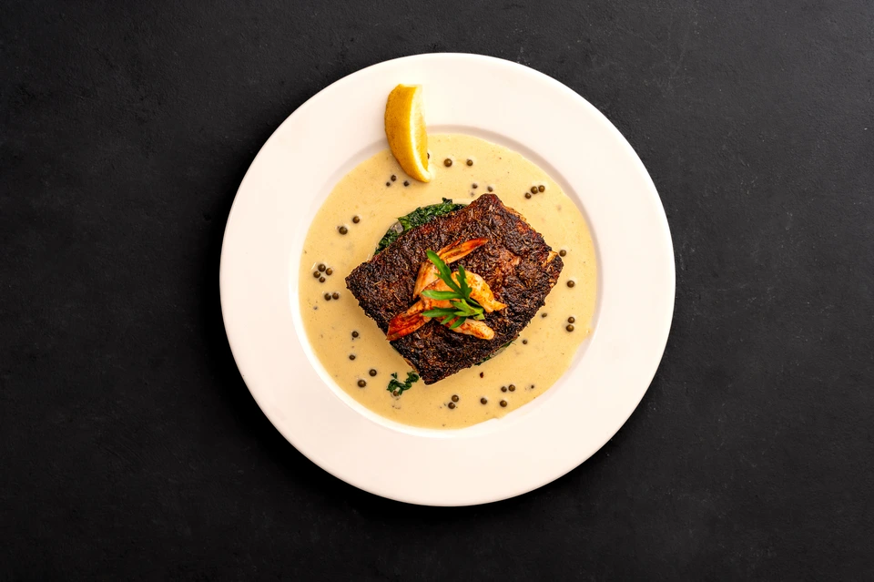 Carefully plated dish on a pale plate against a dark background