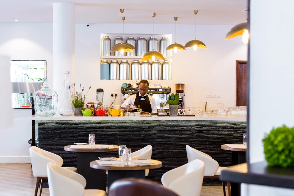 Bright restaurant interior with a curved bar and small tables