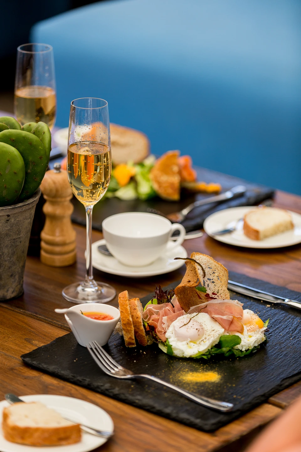 Coffee and food arranged on a restaurant table beside a blue wall