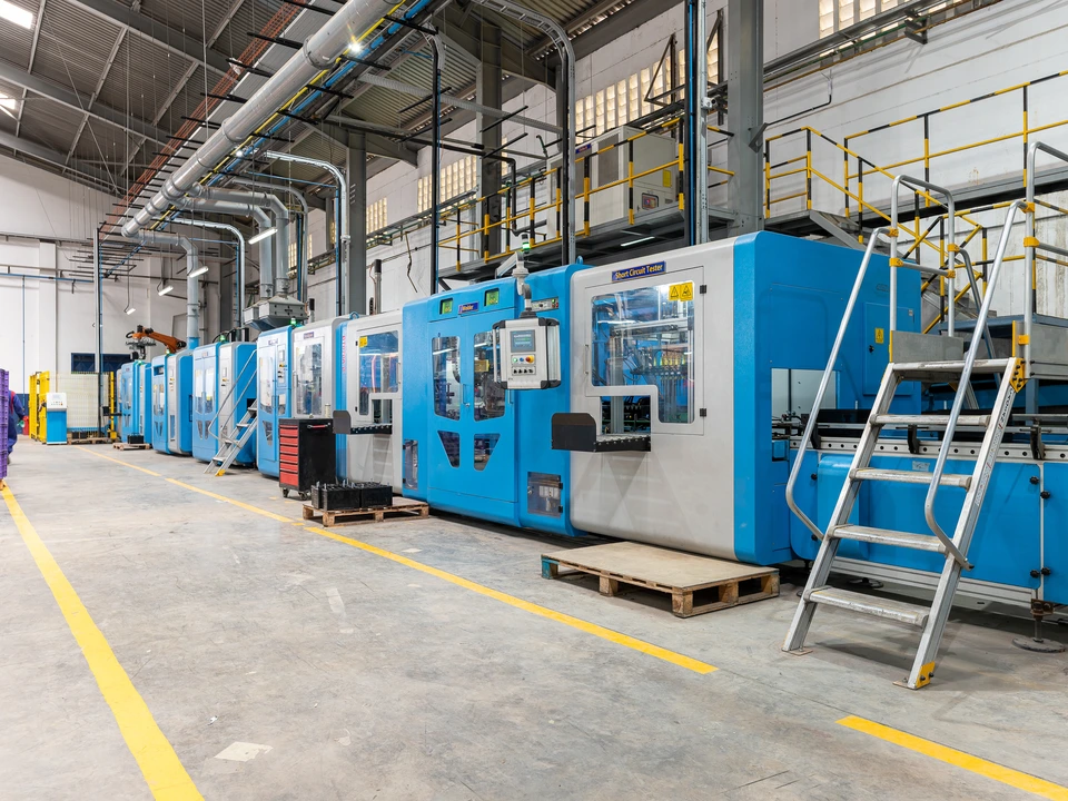 Row of large blue machines inside a bright factory