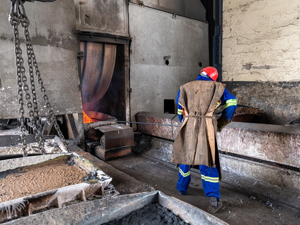 Worker in protective clothing beside large industrial equipment