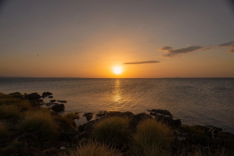 Sunset above a rocky shoreline and calm sea