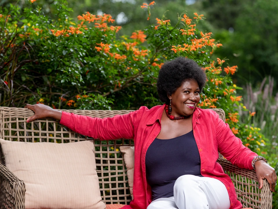 Woman in a red jacket seated in a garden