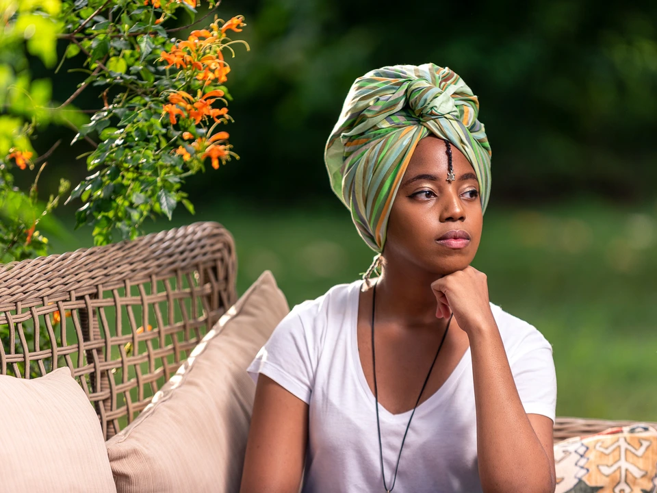 Woman wearing a headwrap seated in a garden