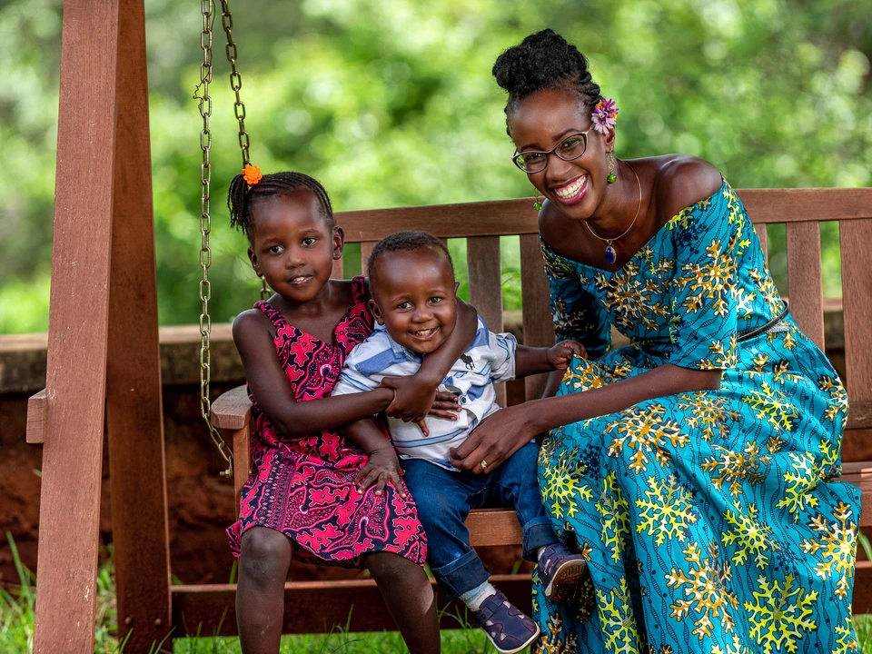 Woman and two children laughing together on a garden bench