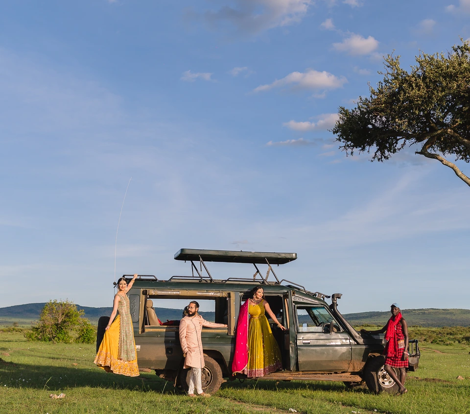 Wedding party beside a safari vehicle and an acacia tree