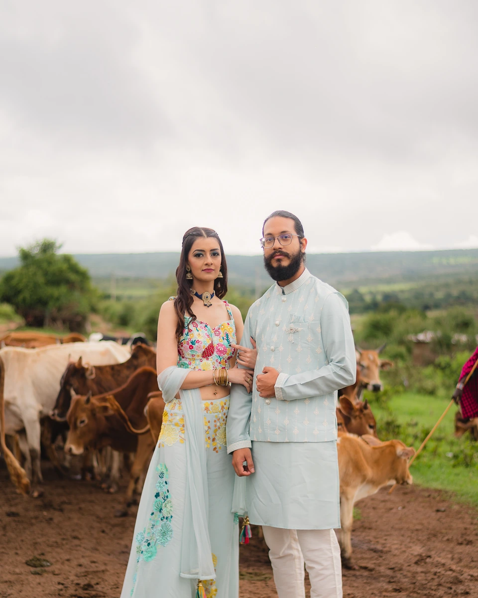 Wedding couple standing together beside cattle in a rural landscape