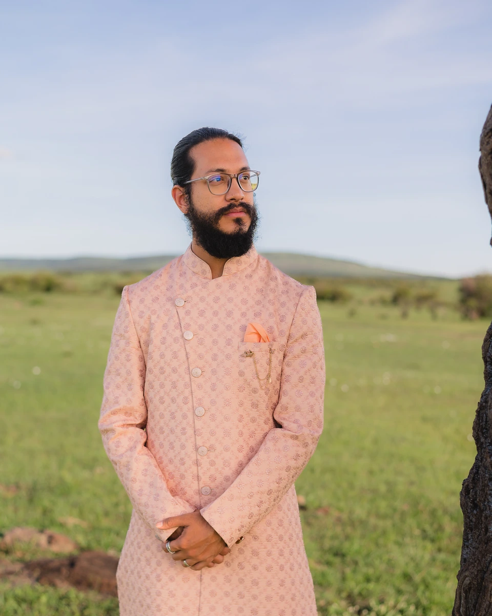 Groom in a pale patterned outfit standing outdoors