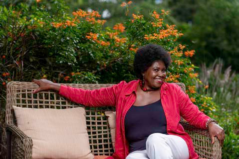 Woman in a red jacket seated in a garden