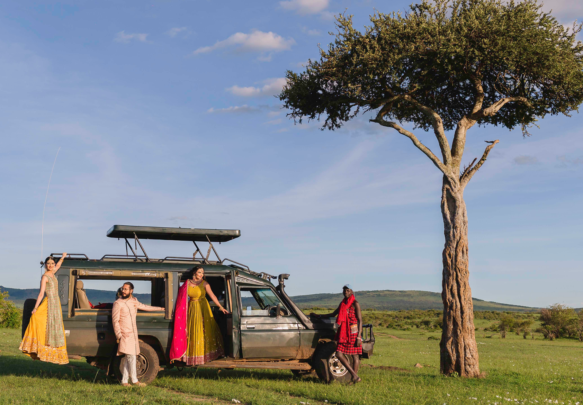 Wedding party beside a safari vehicle and an acacia tree